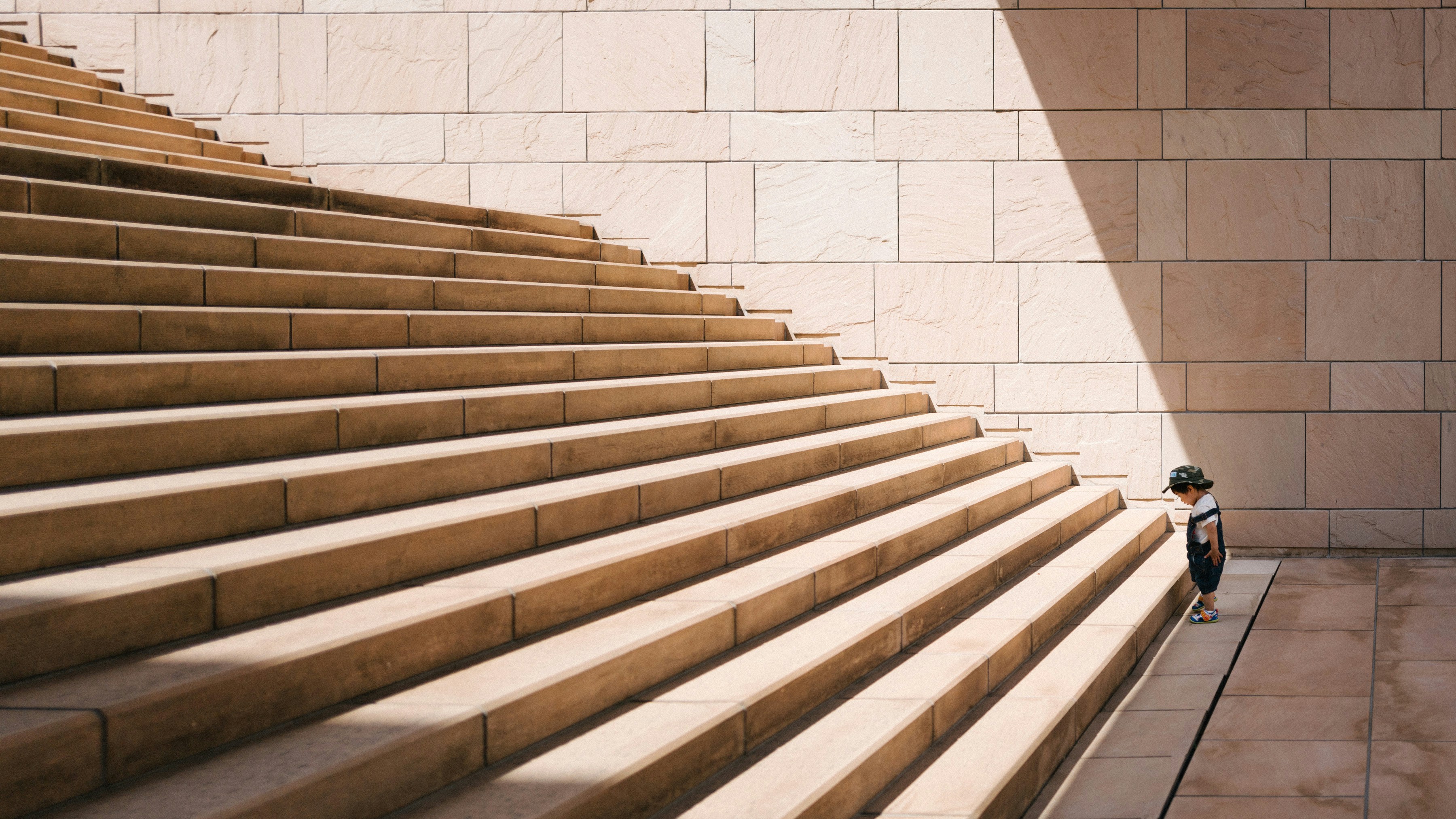 A toddler in dungarees standing in front of a stone staircase